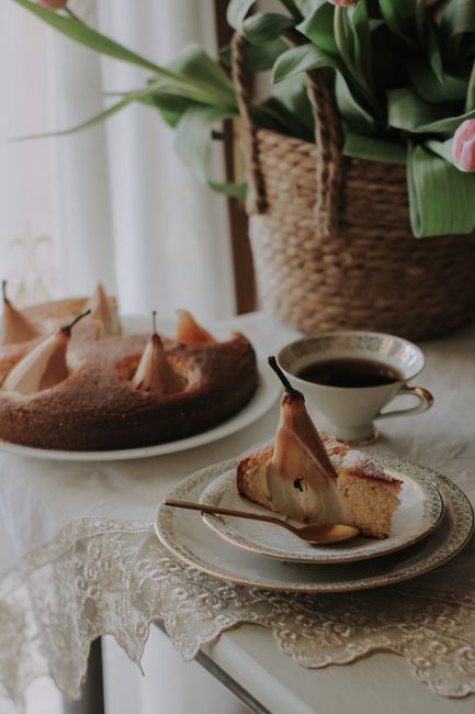 Beautiful food scene with pear cake and coffee on a lace tablecloth.