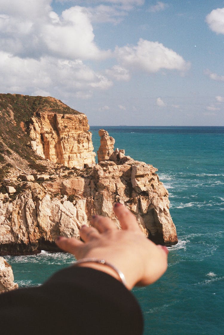 Hand Pointing At Cliff Rocks