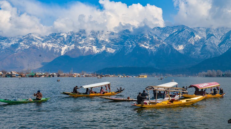 People In Boats On Lake With Mountains Behind