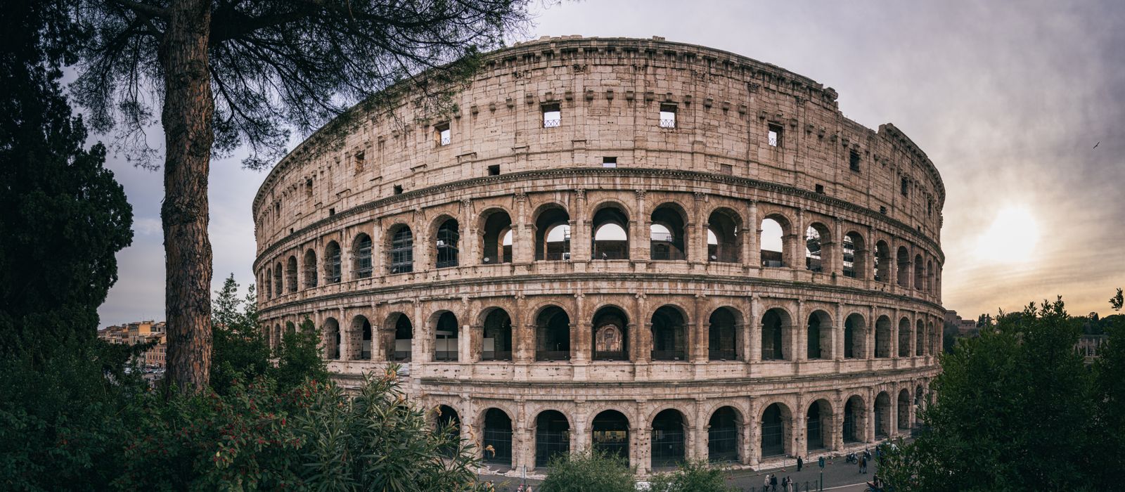 Captivating wide-angle shot of Rome's iconic Colosseum with a serene sunset backdrop.