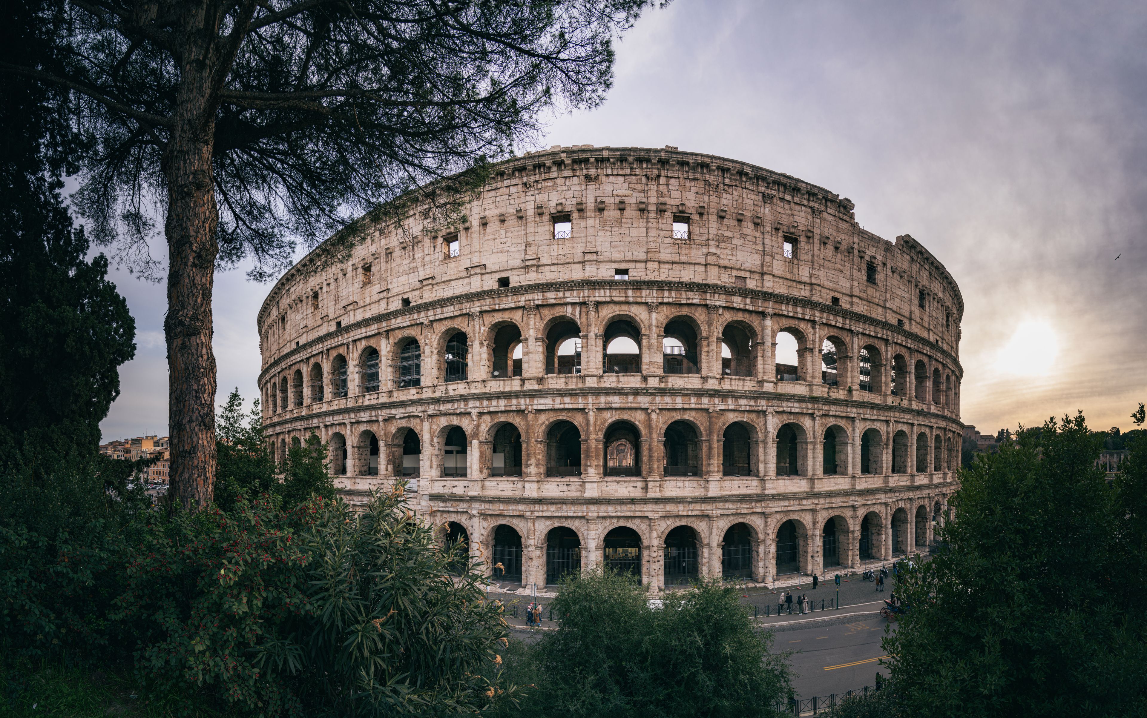 Captivating wide-angle shot of Rome's iconic Colosseum with a serene sunset backdrop.