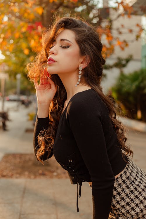 Young Woman Posing on a Sidewalk with Autumnal Trees in the Background 