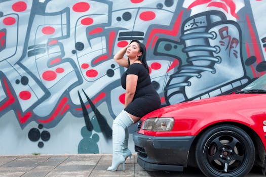 一位时尚女性倚着充满活力的涂鸦墙，在一辆红色汽车旁摆姿势