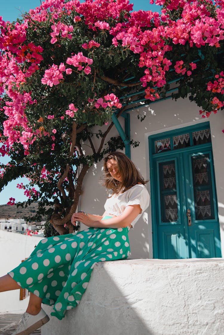 Woman In Skirt Sitting Under Tree With Pink Flowers