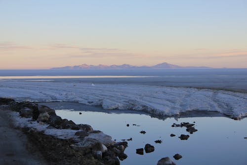 View of a an Icy Flatland and Mountains in Distance at Sunset