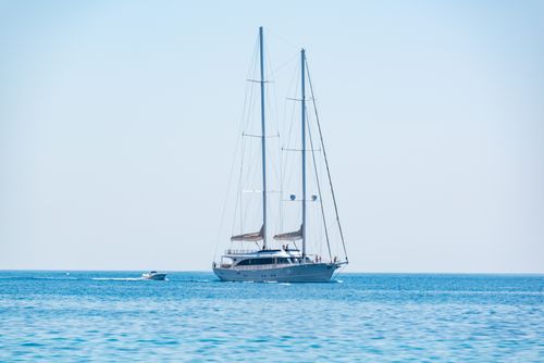 Free Elegant sailing yacht cruising on the calm blue waters under a clear sky. Stock Photo