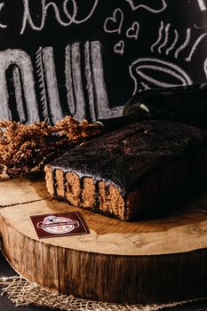 Delicious chocolate cake with icing on a rustic wooden board, perfect for dessert lovers.