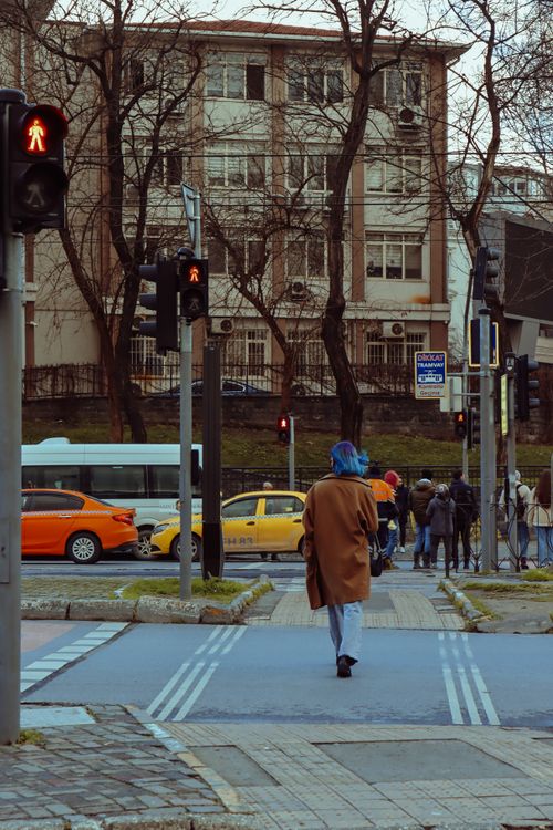 Free A woman crosses a city street under red traffic lights on a chilly winter day. Stock Photo