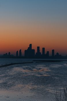 A striking city skyline silhouetted against a twilight sky, reflected in calm waters.. striking, city, skyline