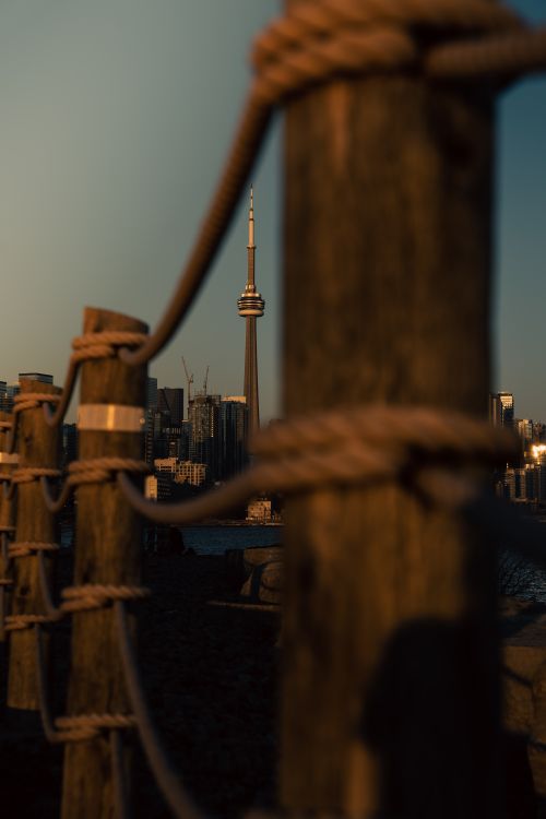 Free Dramatic view of Toronto's CN Tower framed by dock posts at sunset. Stock Photo