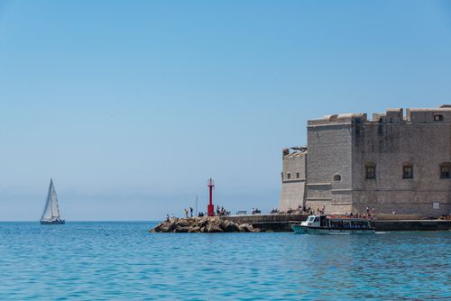Free Fortified structure near Dubrovnik with boats and a sailboat on a sunny day. Stock Photo