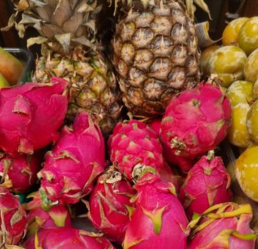 Close-up of fresh pineapples and vibrant dragon fruits in a market setting.