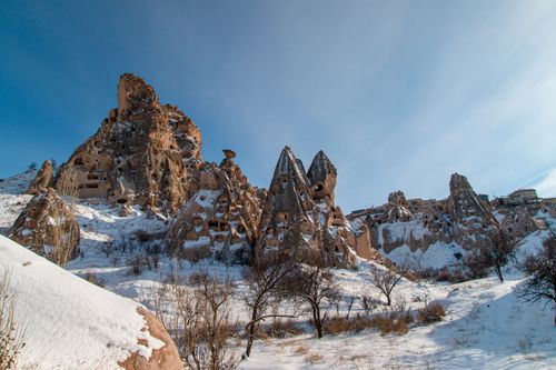Free Snow-covered rock formations in Cappadocia under a clear blue sky. Stock Photo