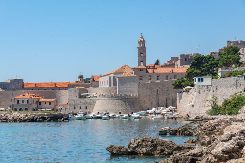 Historic walls and harbor in Dubrovnik, Croatia under a clear blue sky.