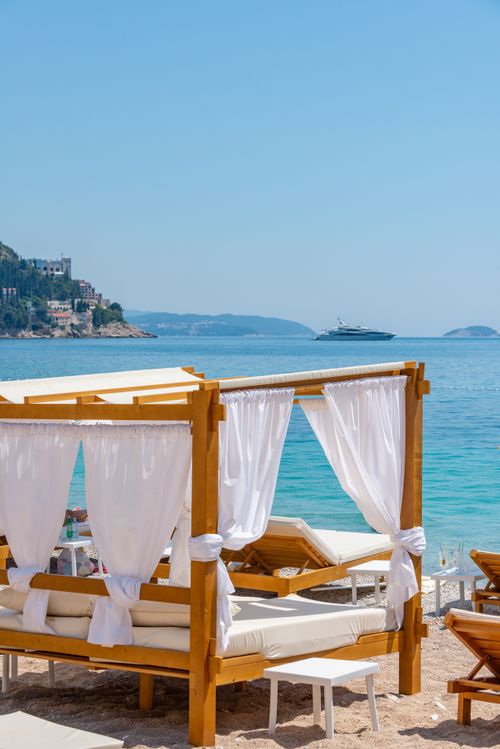 Free Serene beach scene with a stylish canopy and distant yacht on a sunny day. Stock Photo