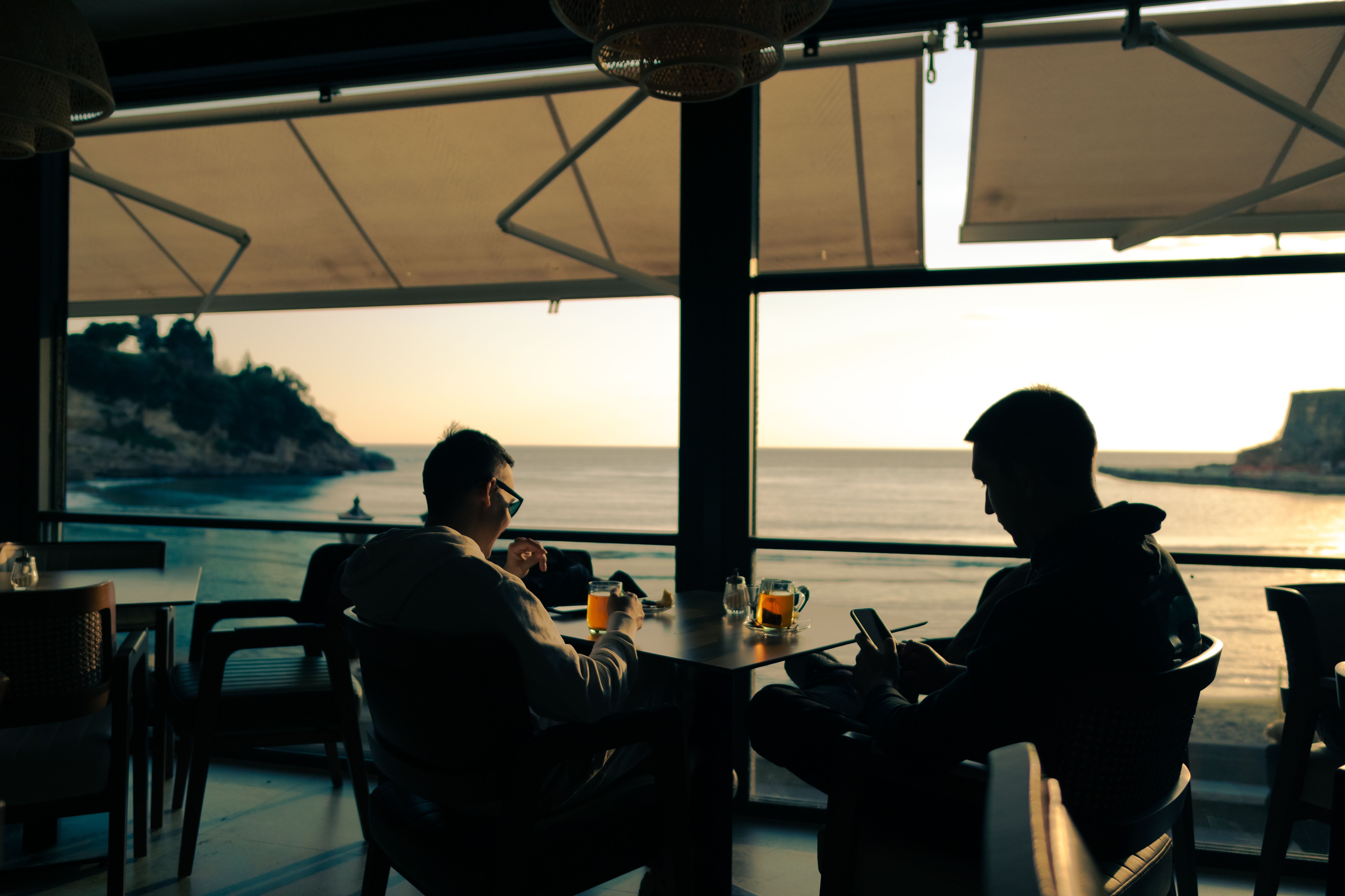 Relaxing ocean view with people dining indoors at sunset in Montenegro.