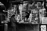 Black and white view of a market stall in Valencia with customers interacting.