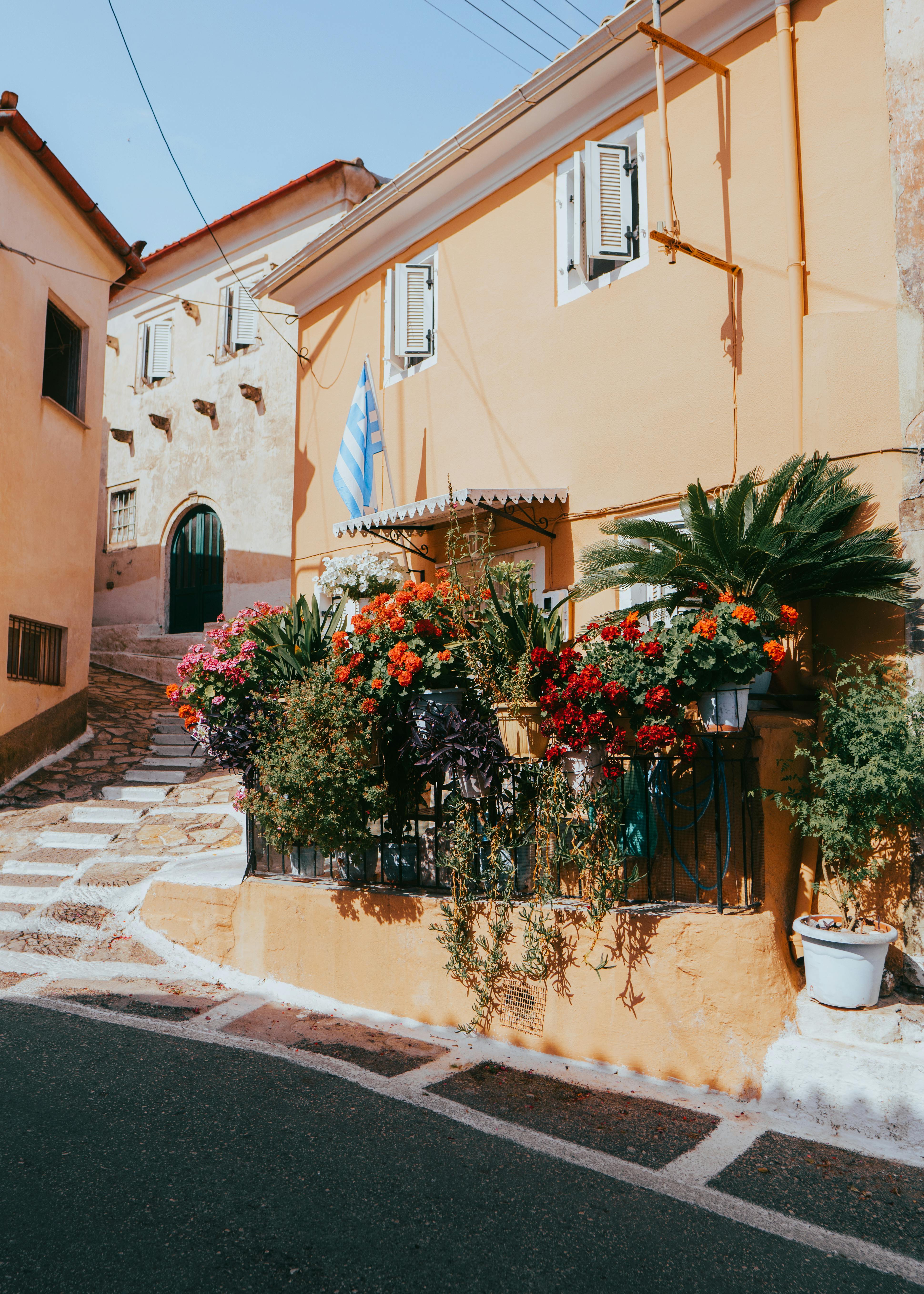 Beautiful floral facade on a sunny street in Kerkyra, Greece, showcasing vibrant Mediterranean architecture.