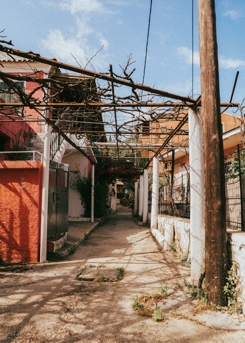 Free Explore a rustic alleyway in Kerkyra, Greece, showcasing vibrant facades and Mediterranean charm. Stock Photo