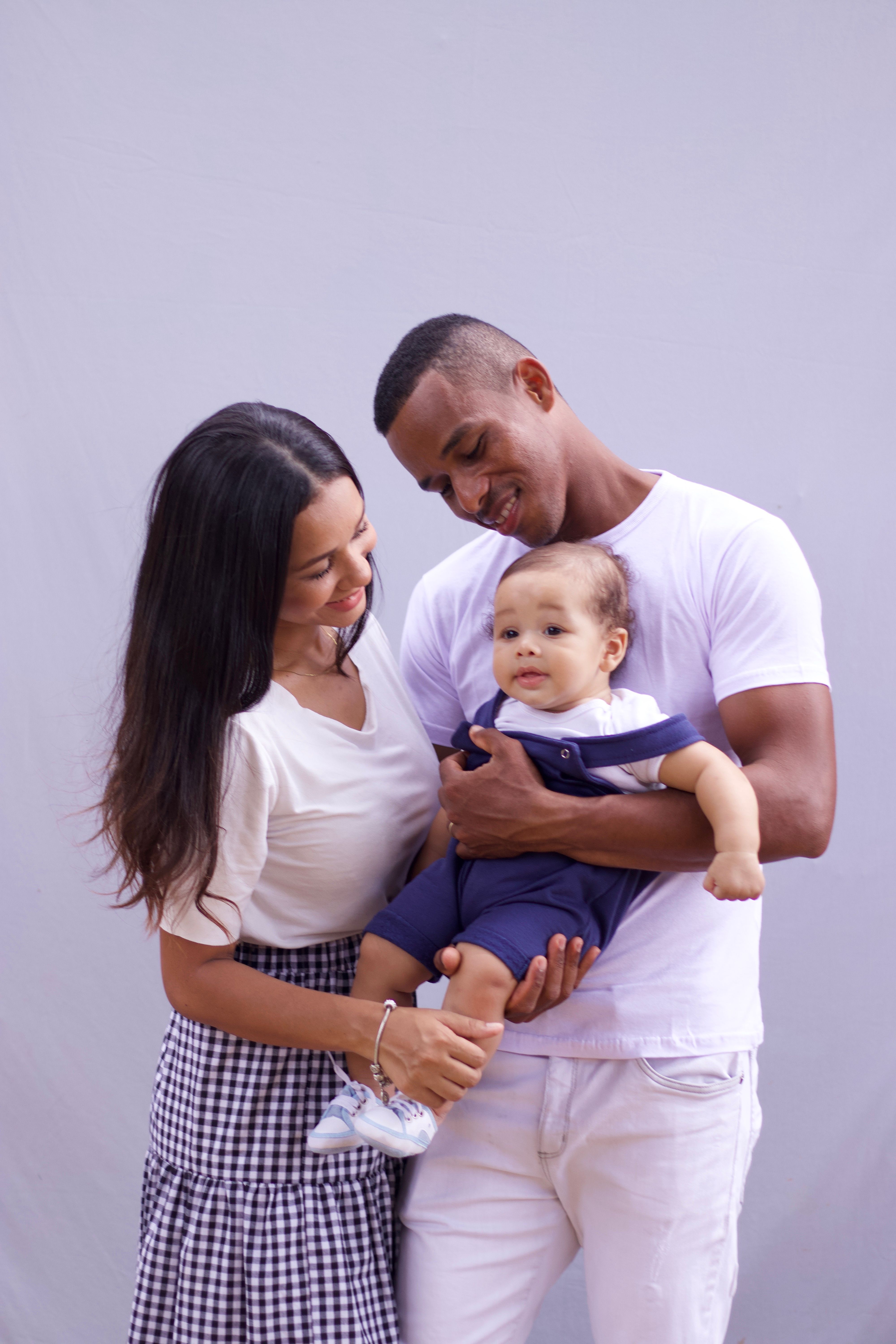 A joyful family portrait featuring a loving couple holding their baby.