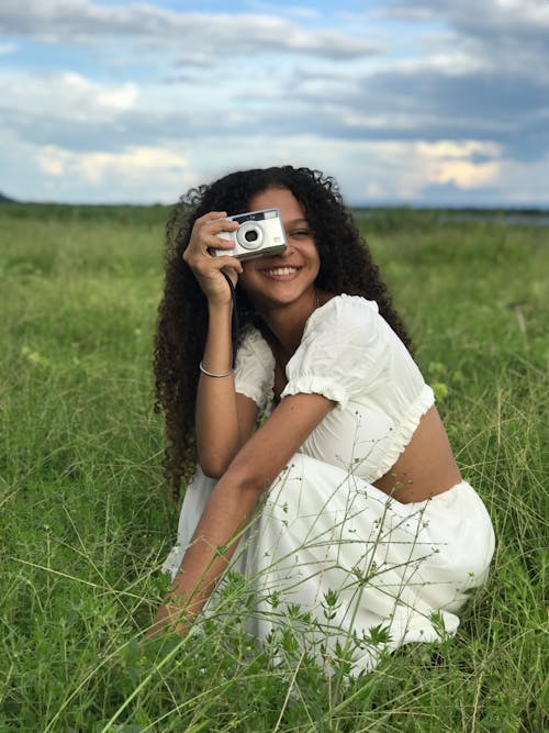 Woman Crouching on Meadow with Camera