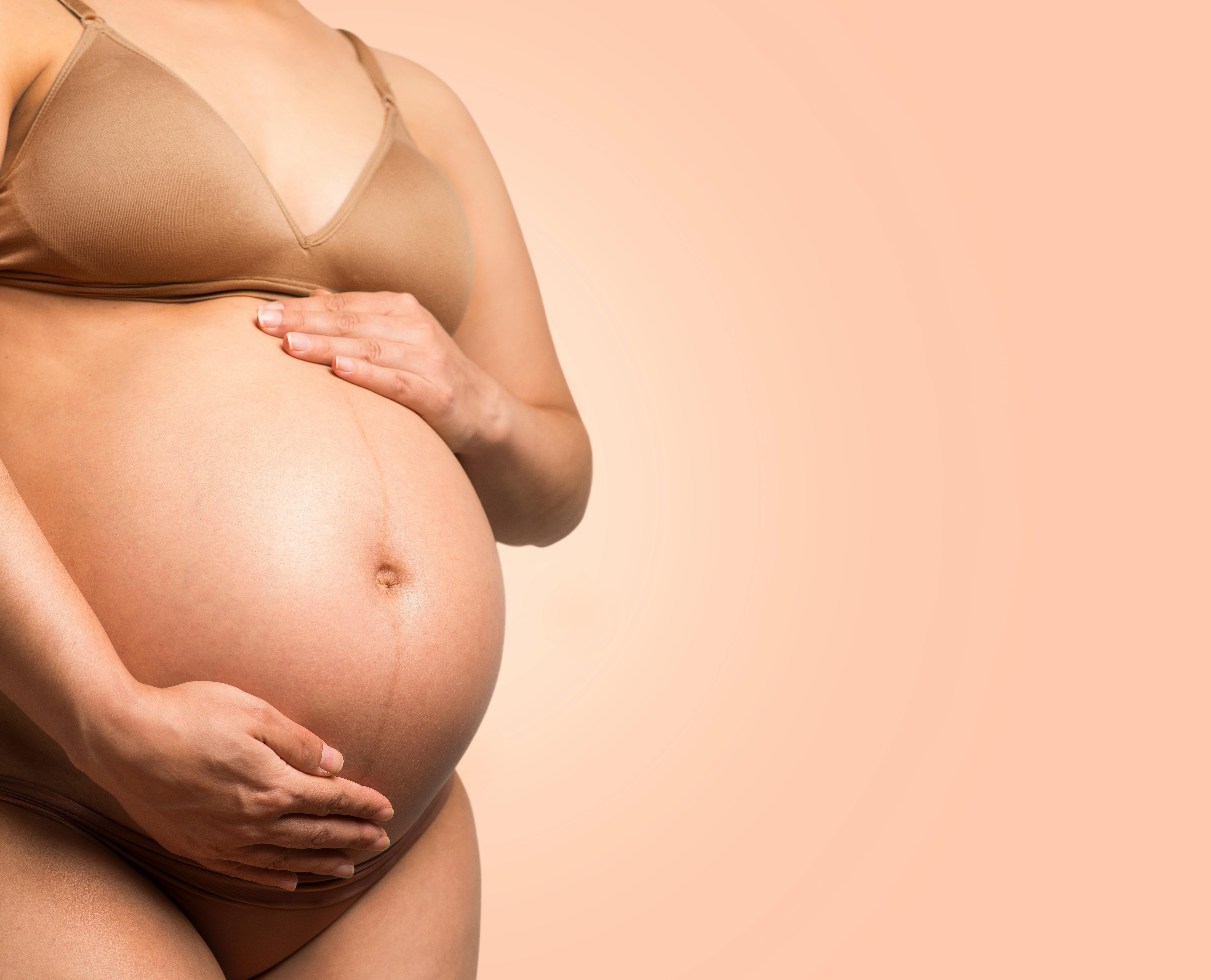 Pregnant woman smiling while resting hands on belly