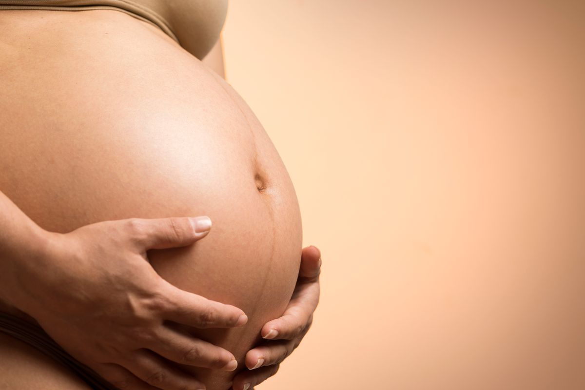 A pregnant woman’s hands resting on her belly