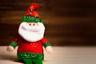 木制桌面上摆放着身穿红绿服装的可爱圣诞老人毛绒玩具，非常适合节日装饰