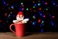 这款红色杯子装饰着雪人，映衬着色彩缤纷的散景灯光，非常适合节日主题