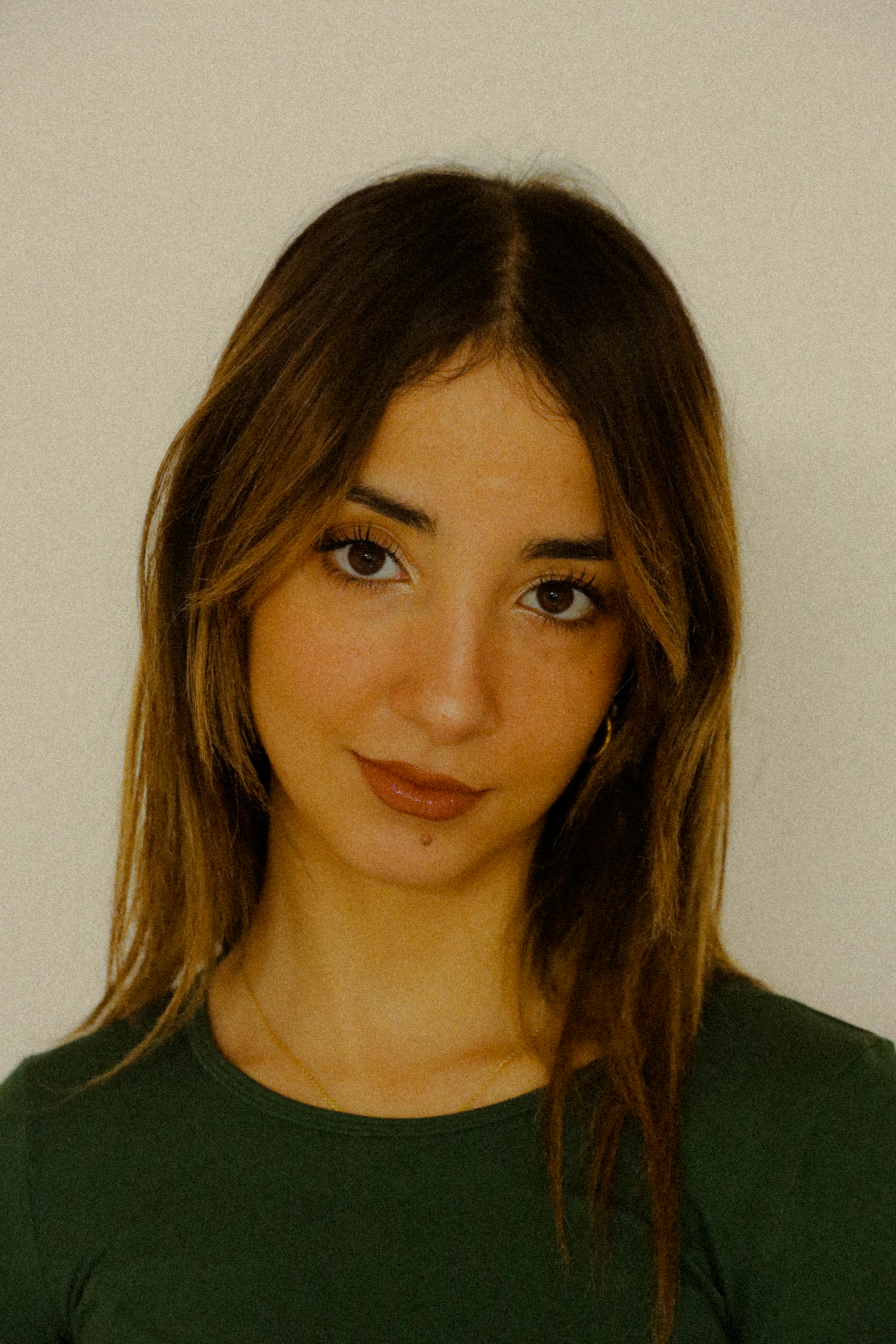 Charming portrait of a young woman with long brown hair against a white background.