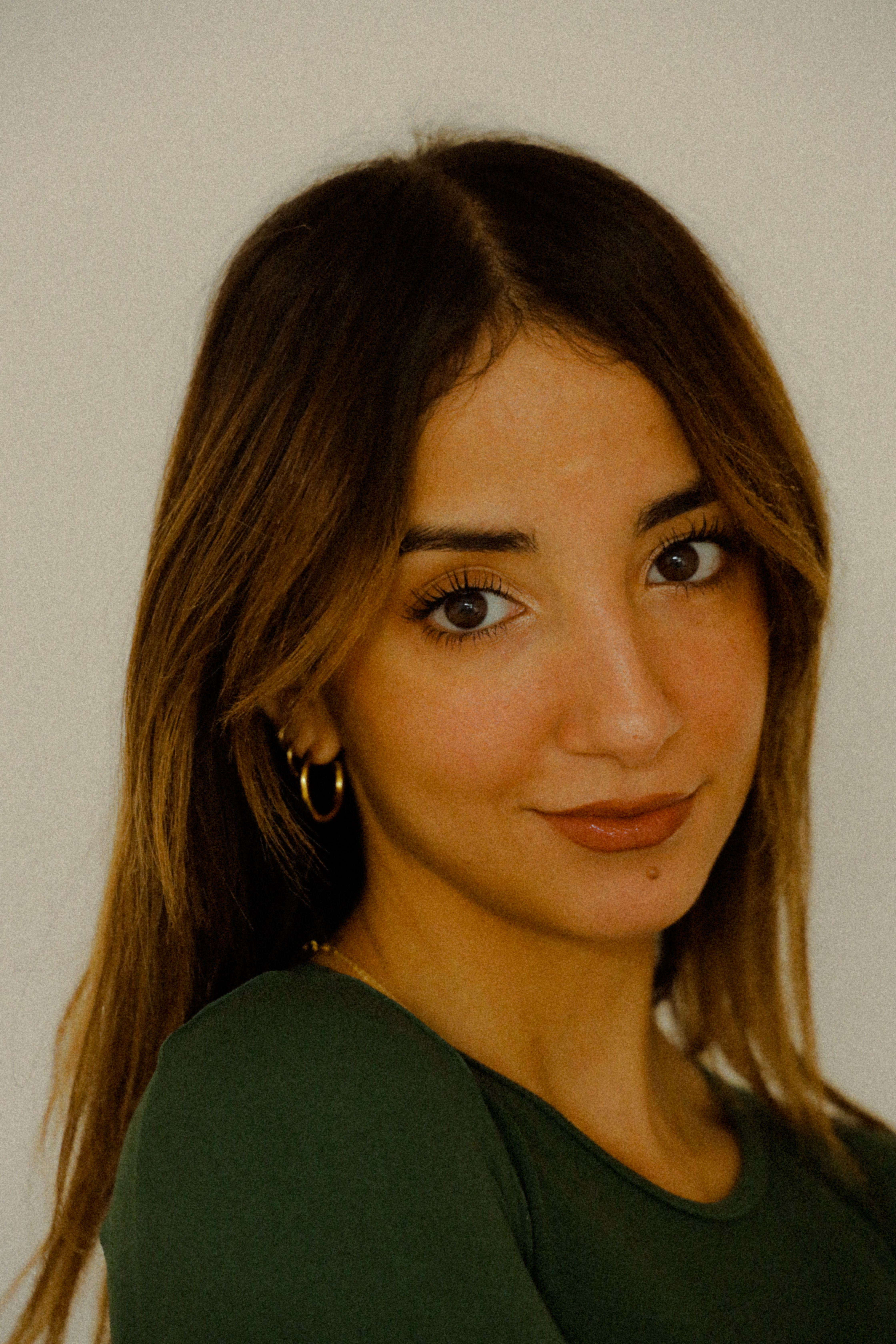 Elegant headshot of a woman with long brown hair smiling against a white background.