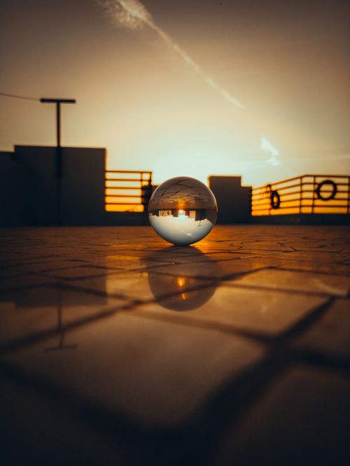 Free Glass sphere capturing a stunning sunset reflection on a rooftop in India. Stock Photo