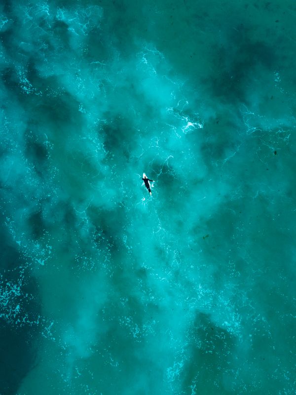 Surfer paddling in turquoise water