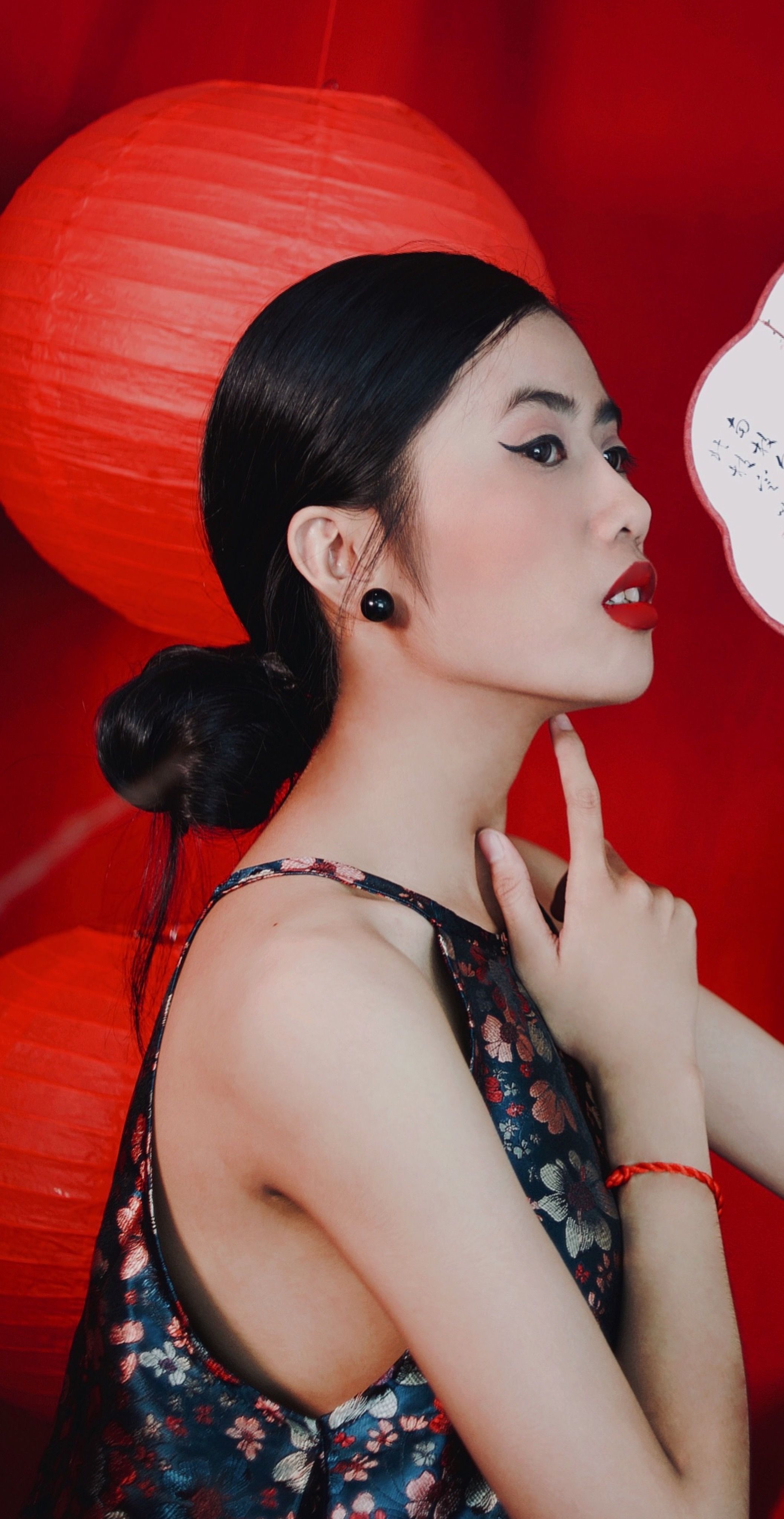 Stylish portrait of a woman posing against red lanterns, showcasing elegance and fashion.