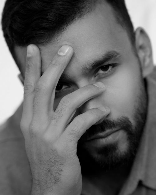 Free Close-up black and white portrait of a man covering his face partially with his hand. Stock Photo