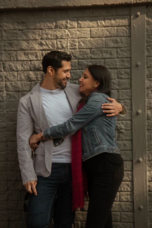 Free A loving couple shares a warm embrace against a textured brick wall in Mexico City. Stock Photo