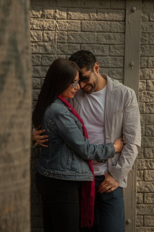 Free A loving couple embraces in a warm and intimate moment against a textured brick wall. Stock Photo