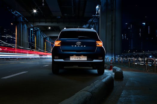 A Hyundai Venue SUV under a city bridge in Seoul at night with striking light trails.