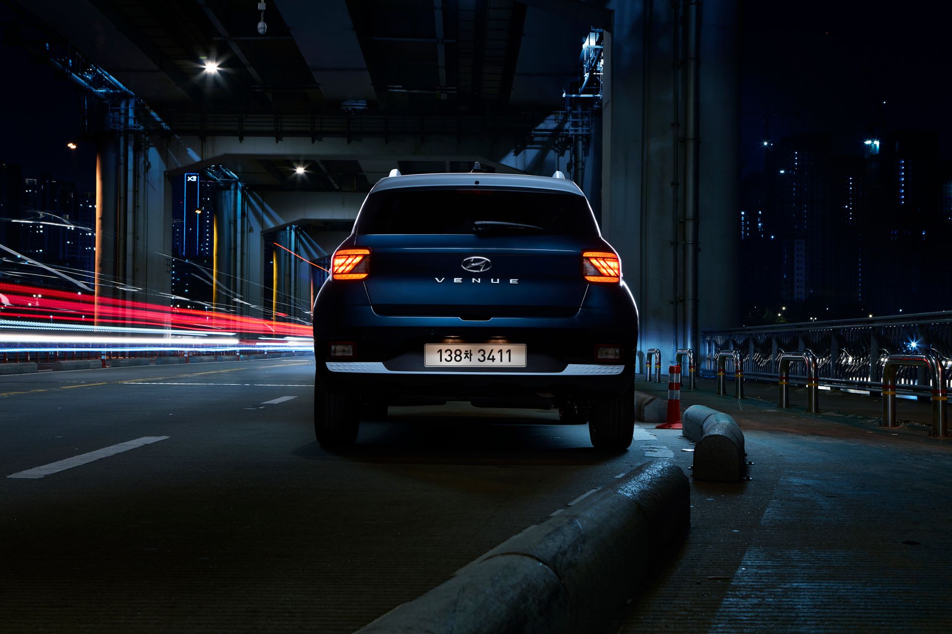A Hyundai Venue SUV under a city bridge in Seoul at night with striking light trails.