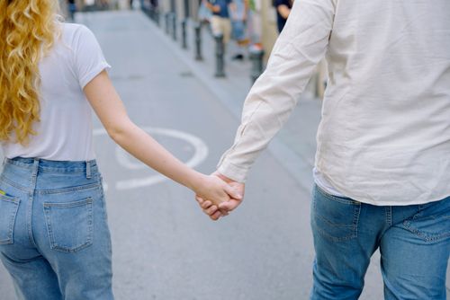 Free A couple holding hands and walking down a bustling city street, capturing romance. Stock Photo