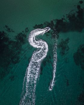 从空中俯瞰，一艘快艇在墨尔本的海水中划出漩涡图案