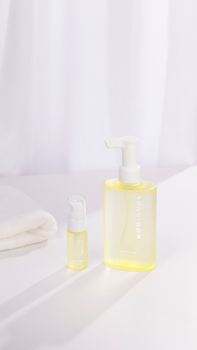 Two clear bottles with yellow liquid on a white surface, showcasing skincare simplicity.