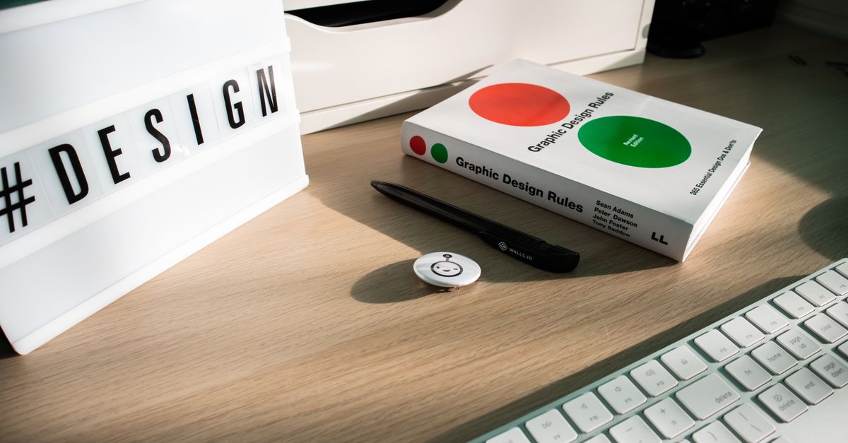 A modern desk setup featuring design elements like a book, #DESIGN sign, and accessories.