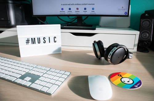 Free A creative desk setup featuring headphones, keyboard, mouse and a music-themed lightbox. Stock Photo