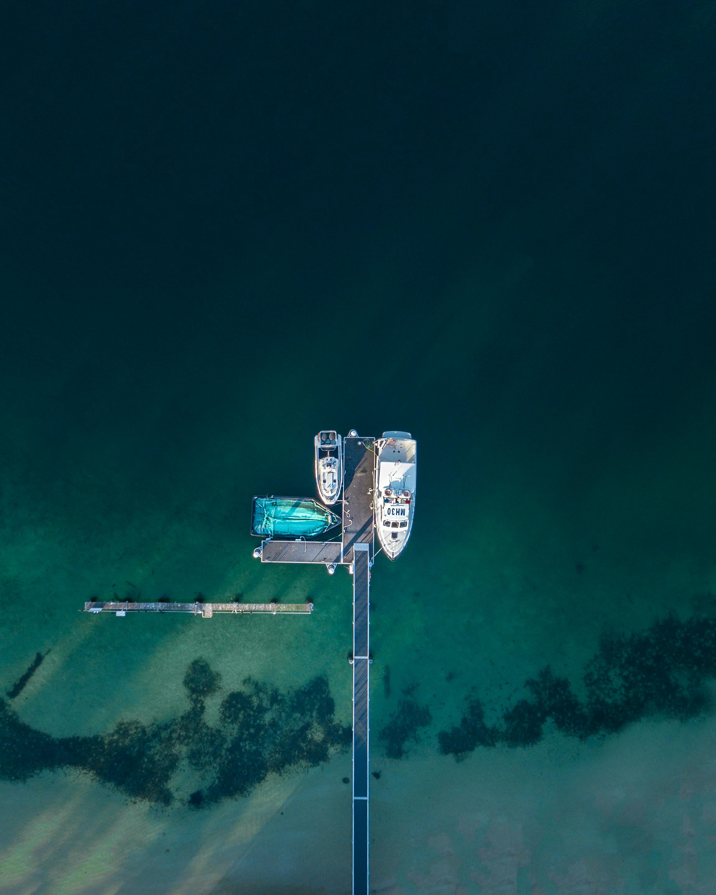 航拍画面中，悉尼码头停泊着船只，水域清澈