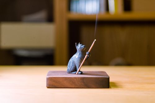 Free Elegant cat figurine incense holder with gentle smoke trail on wooden base. Stock Photo