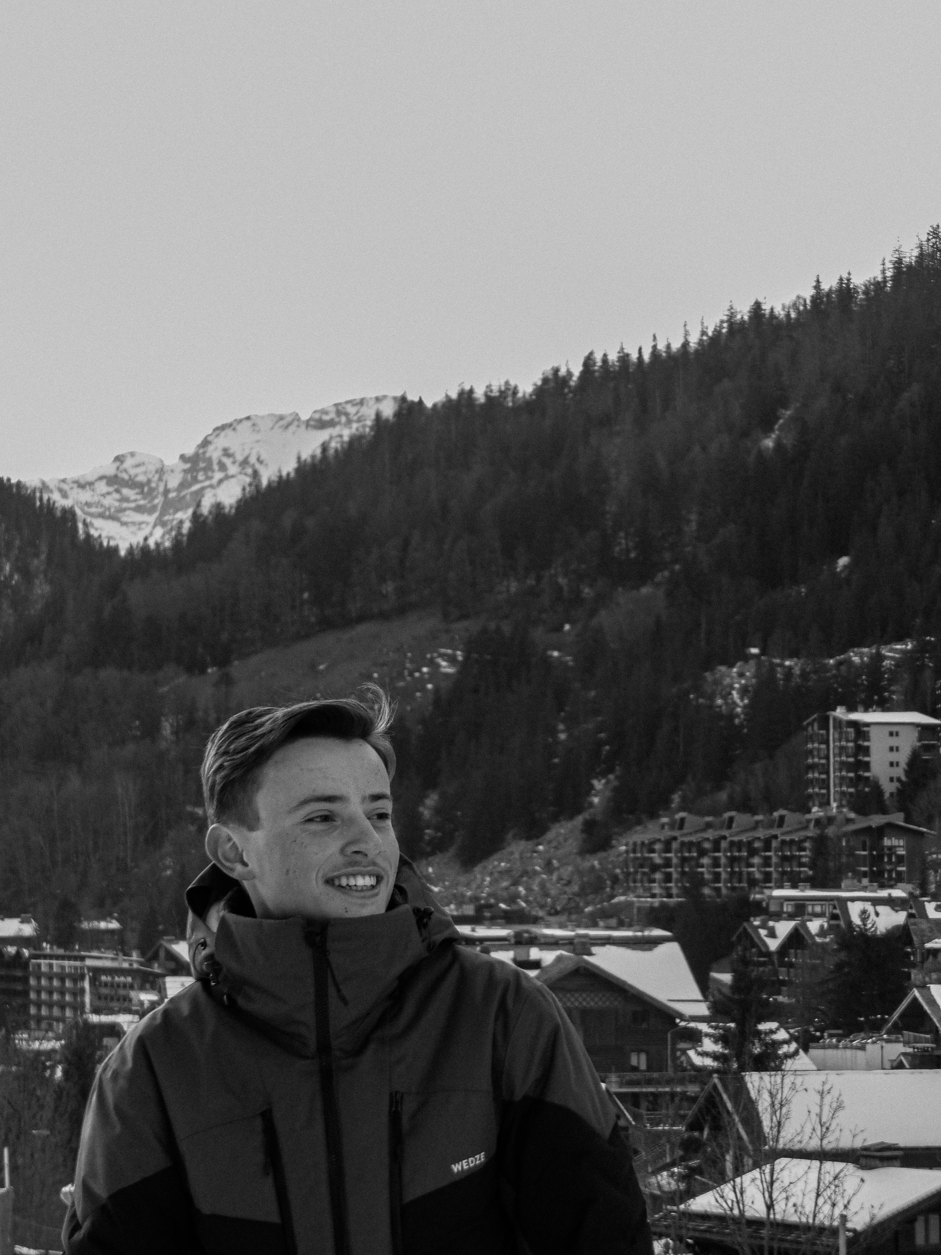 Prescription Goggle Inserts - Smiling man in winter jacket with snowy mountain backdrop in La Clusaz, France.