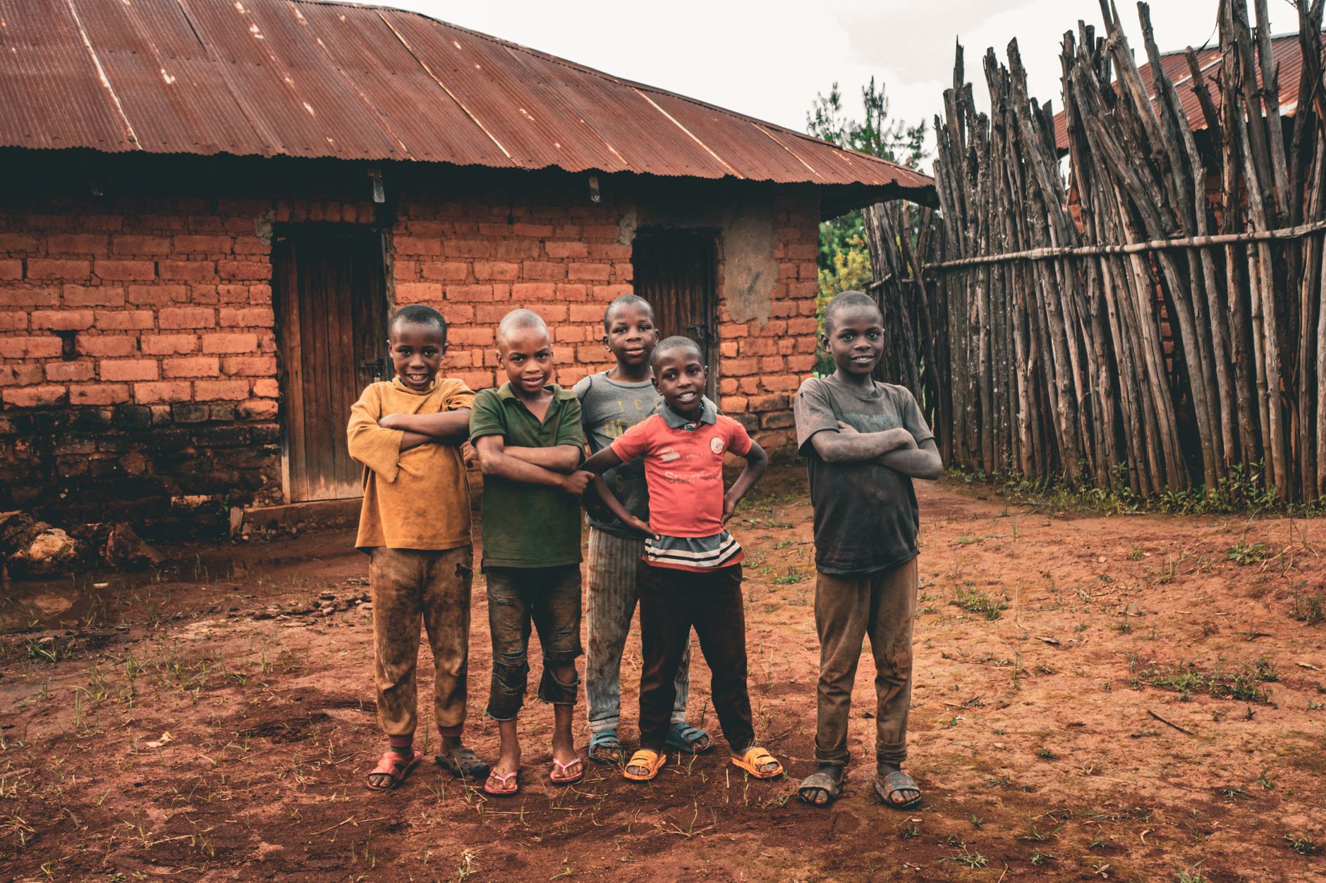 Group of smiling children standing in front of a rustic house in Makete, Tanzania.