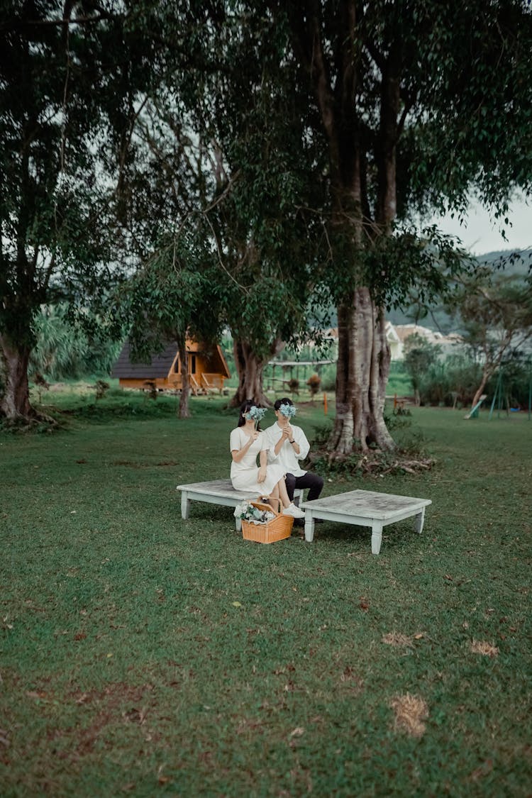 Man And Woman Sitting On Bench, Covering Face