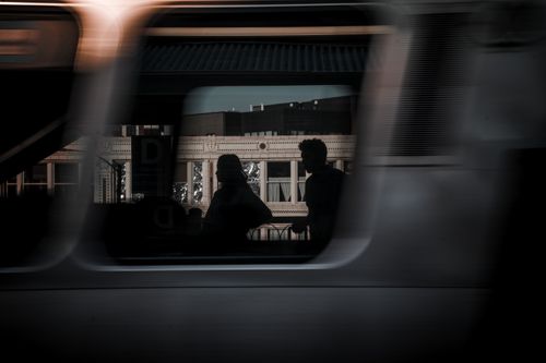 Free Silhouettes of people seen through a moving train window with sunlit building in background. Stock Photo